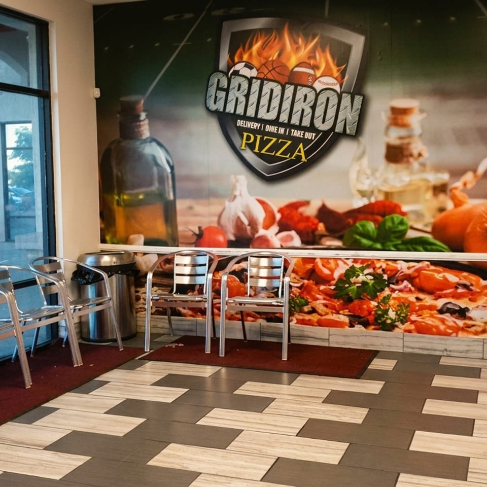 Gridiron Pizza restaurant interior with a large pizza mural, seating, and a drink cooler.